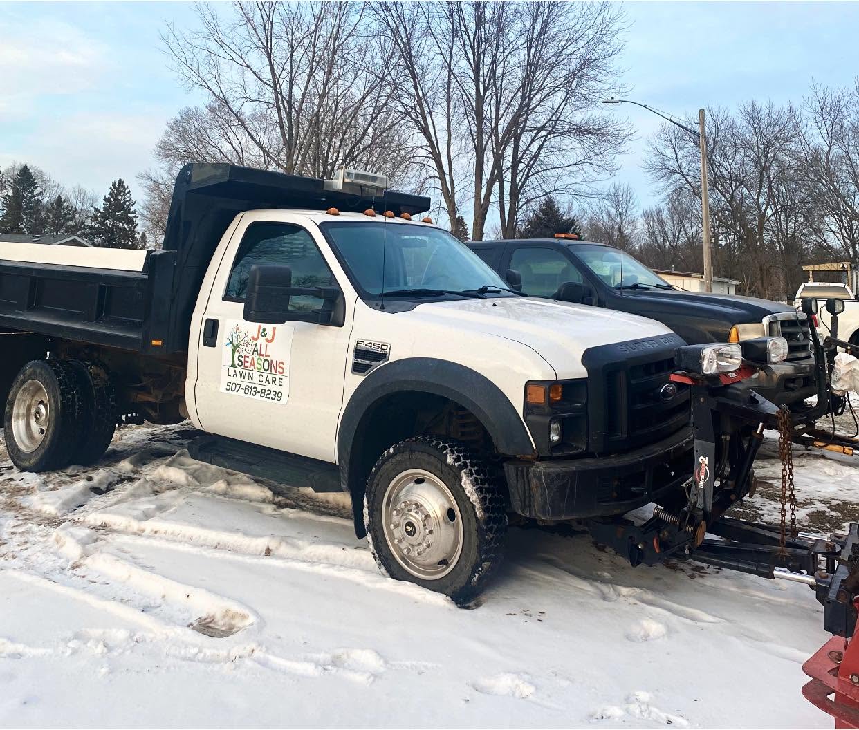J&J All Seasons Lawn Care branded truck with snow plow, ready for winter service
